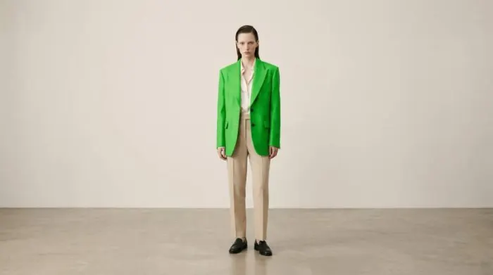 Model wearing vivid arsenic green outfit against neutral background showing bold modern fashion statement with toxic color contrast