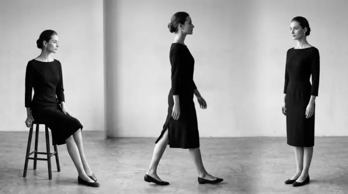 Woman wearing Givenchy style black dress with bateau neckline and back slit showing structured elegance of Audrey Hepburn iconic look Woman wearing Givenchy style black dress with bateau neckline