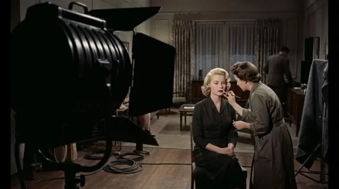 1950s Hitchcock-inspired heroine receiving precise sculptural makeup on a film set 1950s Hitchcock-inspired heroine receiving precise sculptural makeup on a film set