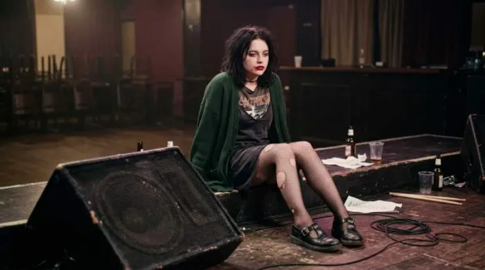1990s Riot Grrrl musician styling Mary Jane shoes with ripped fishnets