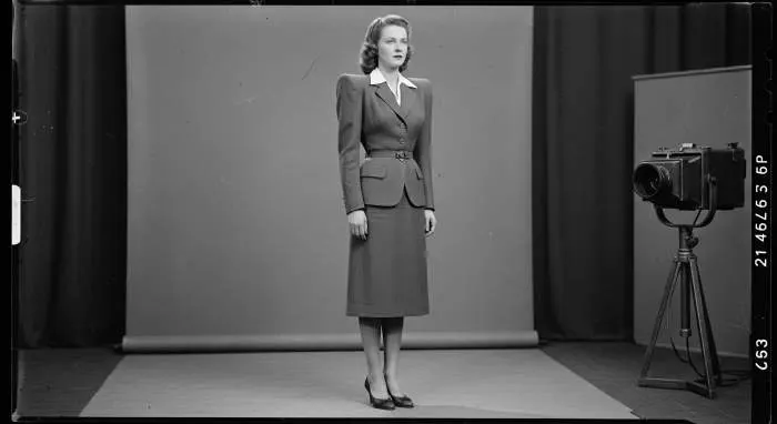 Woman in 1940s padded shoulder suit with broad shoulders and tailored silhouette