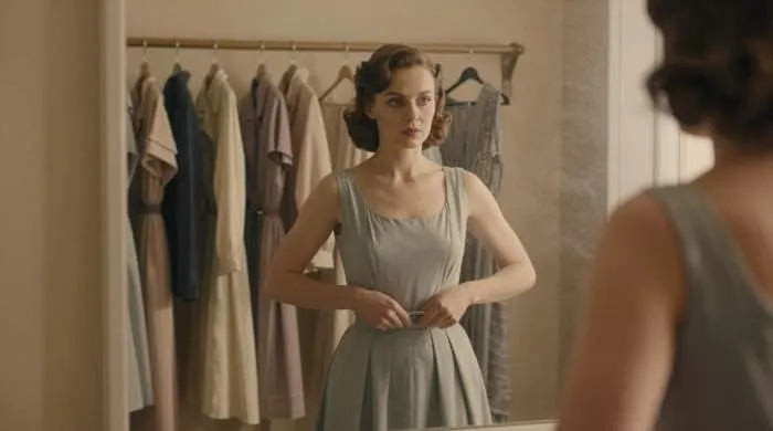 Woman in 1940s crop top examines her reflection, symbolizing fashion autonomy and control.