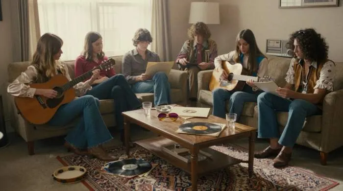 Woman in 1970s boho outfit with flared jeans and fringe in a retro living room
