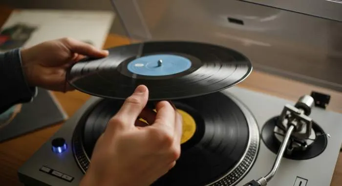 A person placing a vinyl record onto a turntable during a listening ritual